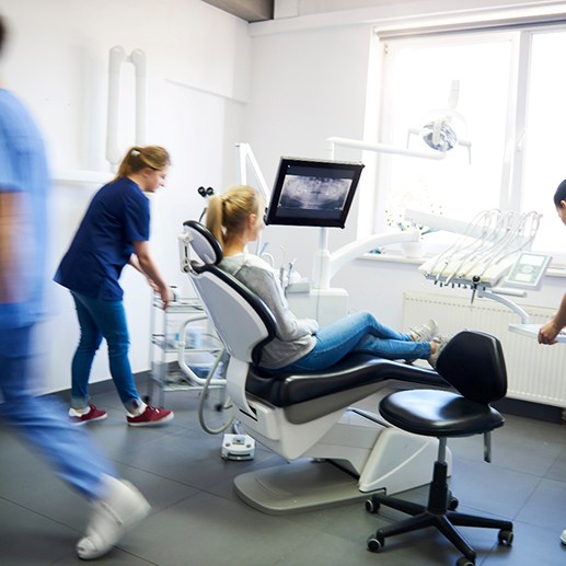 A blurred view of dentists and a woman in a dental clinic