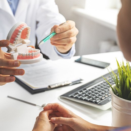 Dentist pointing to model of teeth in office