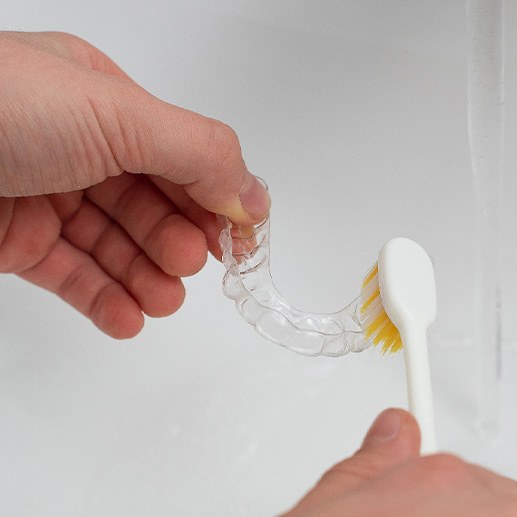 Patient cleaning clear aligner in sink