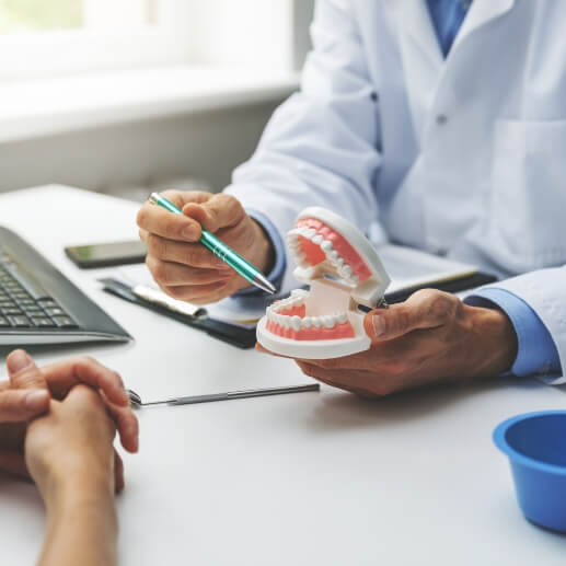 Dentist showing a denture to a patient in Frisco dental office