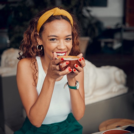 Woman smiling while enjoying cup of coffee
