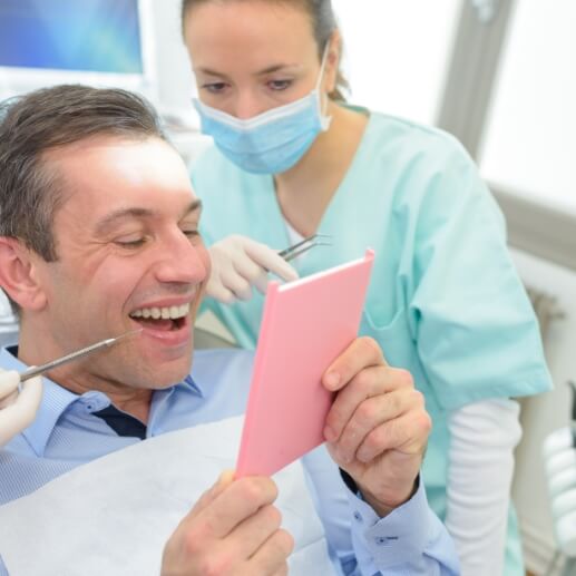 Dental patient admiring his smile in mirror