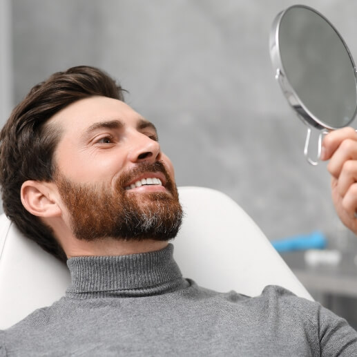 Dental patient looking at his smile in mirror