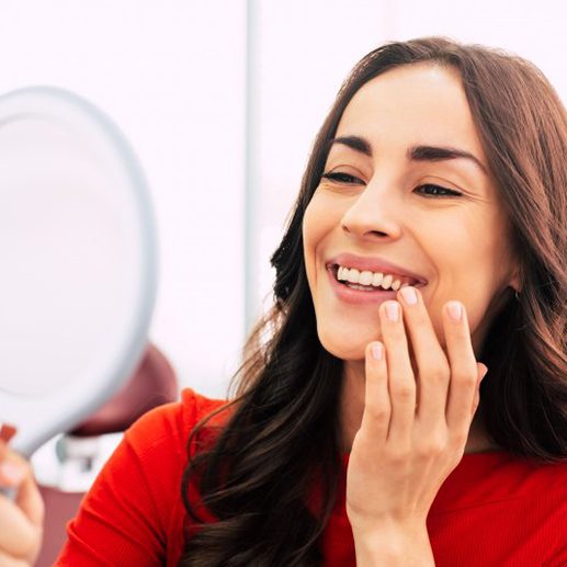 Woman admiring her teeth in small mirror