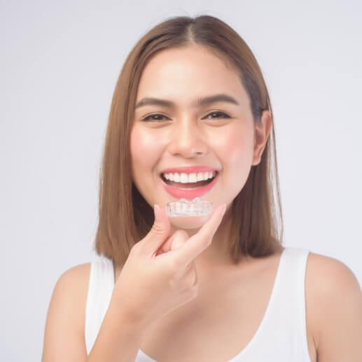 Smiling woman holding an Invisalign aligner near her mouth