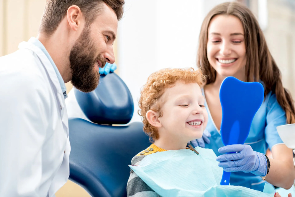 Young boy in dental chair looking at his reflection after dental services in Frisco