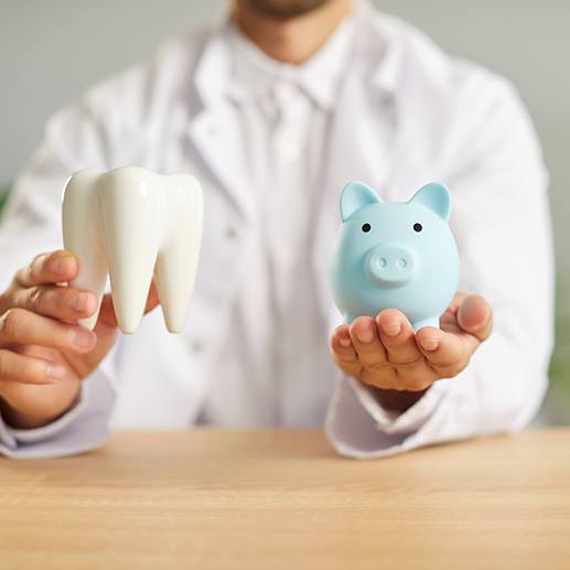A dentist holding a piggy bank and a large white tooth model