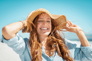 Woman in beach hat smiling in the sun at the beach