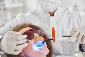 Dentist performing in-office teeth whitening for a patient with curing light