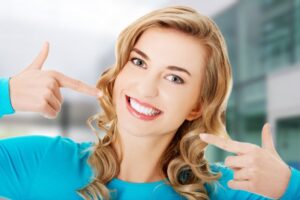 Woman pointing to her pretty straight teeth. 